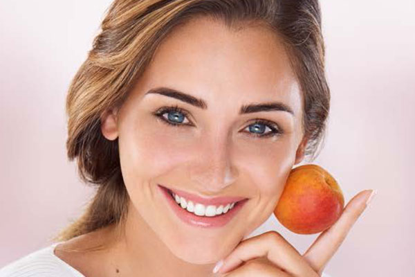 Femme souriante tenant un abricot