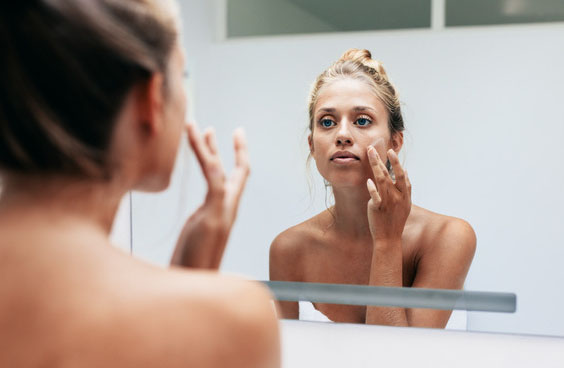 Femme devant un miroir qui protège sa peau